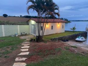 une petite maison avec un palmier à côté de l'eau dans l'établissement Casa à beira lago de Furnas. (Pé na água), à Formiga