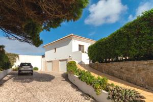 a car parked in front of a white house at Family beach house, sea view, pool, Colares near Sintra in Colares