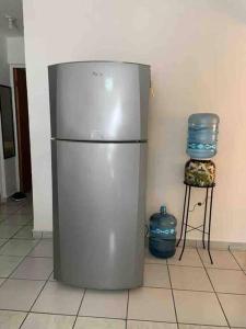 a silver refrigerator in a kitchen with a stool and a table at Depa Los abuelos en Puerto Vallarta in Puerto Vallarta