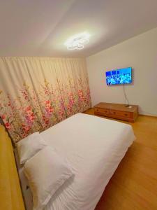 een slaapkamer met een wit bed en een televisie bij LukApartaments in Tulcea