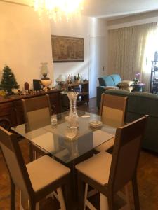 a dining room with a glass table and chairs at Quarto em apartamento in São Paulo