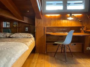 1 dormitorio con cama, escritorio y silla en Mansarda nel centro di Cortina, en Cortina dʼAmpezzo
