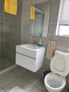 a bathroom with a white toilet and a sink at Tranquil Gateways-The blyde crystal lagoon in Pretoria