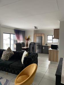 a living room with a black couch and a kitchen at Tranquil Gateways-The blyde crystal lagoon in Pretoria