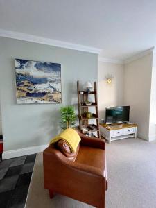 a living room with a couch and a television at Stylish apartment with free parking, lift & views in Scarborough