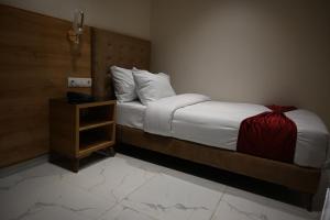 ein Schlafzimmer mit einem Bett mit einer roten Decke und einem Nachttisch in der Unterkunft Motel Abdelhamid in Ouled Moussa