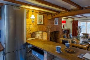 eine Küche mit einer Theke und einem gemauerten Kamin in der Unterkunft 14th-century cosy 3-bed cottage Business stays in Bloxham