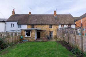 ein altes Steinhaus mit einem Zaun und einem Hof in der Unterkunft 14th-century cosy 3-bed cottage Business stays in Bloxham