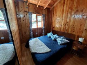 a bedroom with a blue bed and a window at Cabaña La Terraza in Villarrica