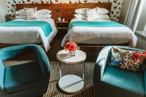 um quarto com duas camas e uma cadeira e uma mesa em The Grove Hotel em Kingsville