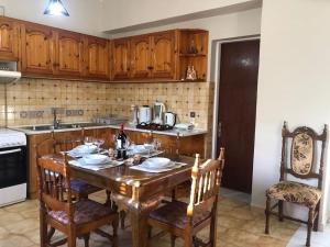 Earthly Paradise في Ambelókipoi: مطبخ مع طاولة خشبية مع كراسي واغطية طاولة