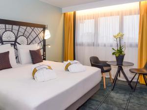 巴黎的住宿－巴黎凡爾賽門展覽中心美居酒店，酒店客房设有一张大床和一张桌子。