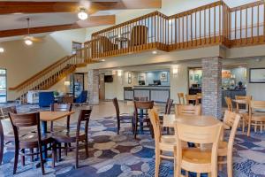 a restaurant with tables and chairs and a staircase at Quality Inn in Oshkosh