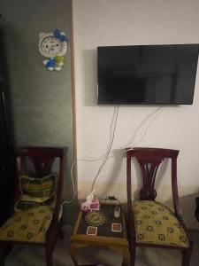 2 Stühle und ein Tisch mit einem TV an der Wand in der Unterkunft Studio makram Ebid in Kairo