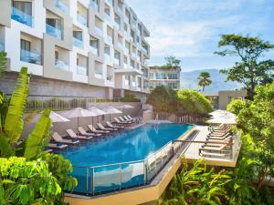 パトンビーチにあるAndaman Beach Hotel Phuket - Handwritten Collectionのラウンジチェアとパラソル付きのスイミングプールを併設しています。