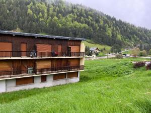 ein Gebäude mit einem Balkon auf einem Feld mit einem Berg in der Unterkunft Le Veymont Élégance Montagnarde in Villard-de-Lans