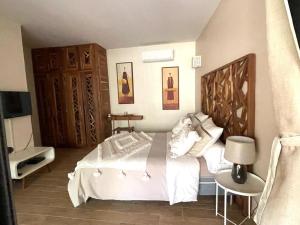 - une chambre avec un lit blanc et une tête de lit en bois dans l'établissement Villa YEMAYA - Suite bungalow indépendant, à Ngaparou