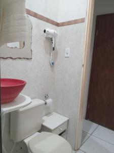 a bathroom with a toilet and a red bowl on the wall at Pousada Villas Colossos in Lençóis