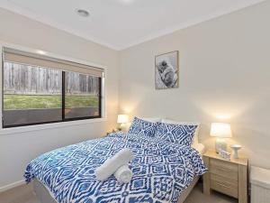 Wandin North11a Railway Parade Wandin North的卧室配有蓝色和白色的床和窗户。