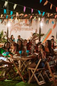 a group of people sitting at a table at a party at Indiana Kite school and Hostel in Cumbuco +85 photos