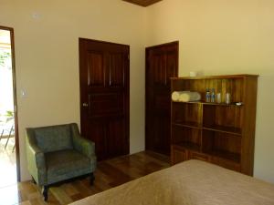 een slaapkamer met een stoel en een boekenplank bij Jardines del Golfo in Lepanto