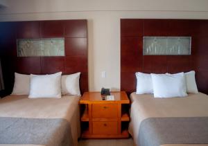 a hotel room with two beds and a wooden table at Del Mar Inn Rosarito in Rosarito