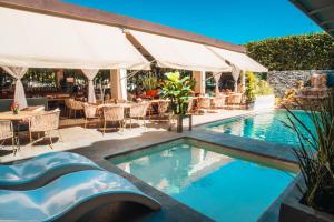 a swimming pool with tables and chairs and a restaurant at Eco City Hoteles in Tuxtla Gutiérrez