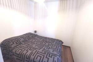 Bett in einem Zimmer mit einer weißen Wand in der Unterkunft Superbe appartement au pied des pistes in La Feclaz