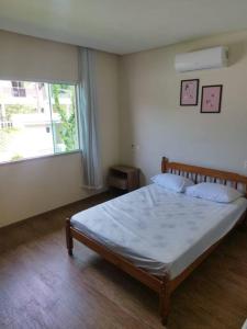 a bedroom with a bed and a large window at Casa com piscina em Zimbros in Bombinhas