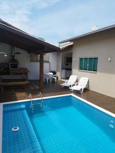 uma piscina com duas cadeiras e uma casa em Casa com piscina em Zimbros em Bombinhas