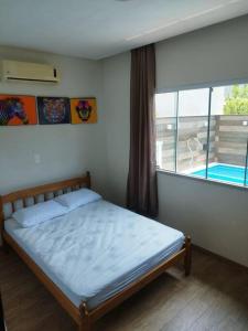 a bedroom with a bed and a large window at Casa com piscina em Zimbros in Bombinhas