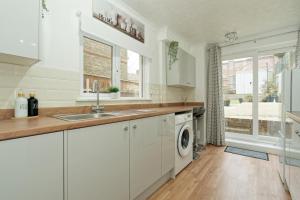 een keuken met een wastafel en een wasmachine bij Lovely Luxury 3 Bed House in Chatham