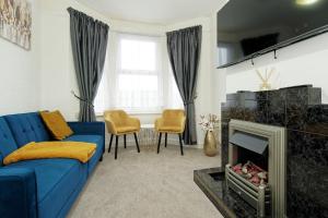 a living room with a blue couch and a fireplace at Lovely Luxury 3 Bed House in Chatham