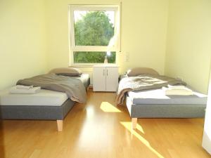 two beds in a room with a window at Schöne Wohnung bis zu 6 Personen in Herzen von Rudersberg in Rudersberg