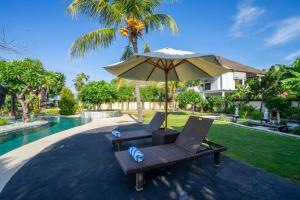 zwei Stühle und ein Regenschirm neben einem Pool in der Unterkunft Lawira Beach Villa Lovina in Lovina