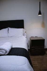 1 dormitorio con cama blanca y mesita de noche en PRANA, en Huancayo