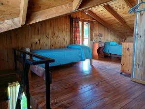ein Schlafzimmer mit einem Bett in einer Holzhütte in der Unterkunft Posada El Maiten in Trevelín