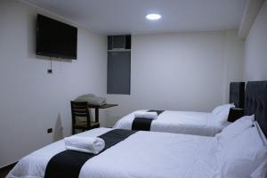 a hotel room with two beds and a television at PRANA in Huancayo