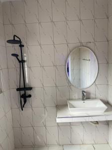 a white tiled bathroom with a sink and a mirror at Le petit coin du paradis in Sintiân