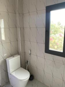 a white toilet in a bathroom with a window at Le petit coin du paradis in Sintiân