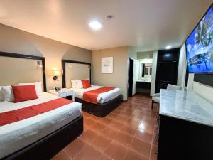 a hotel room with two beds and a flat screen tv at Del Mar Inn Playas in Tijuana