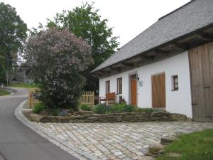 una casa blanca con una pasarela de piedra junto a un árbol en Sunny holiday home near the forest, en Stadlern