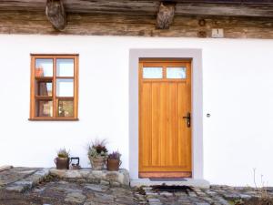 eine Holztür auf einem weißen Haus mit Topfpflanzen in der Unterkunft Sunny holiday home near the forest in Stadlern