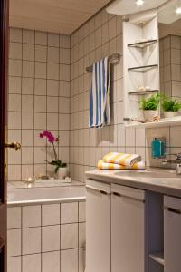 a white tiled bathroom with a sink and a tub at Hotel Neuer Karlshof in Baden-Baden