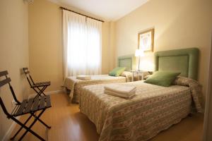 a hotel room with two beds and a chair at Macarena Flat in Seville
