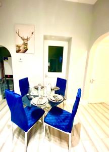 uma sala de jantar com uma mesa de vidro e cadeiras azuis em One Bedroom Ground Floor Flat In Central London em Londres