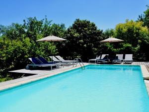 uma piscina com cadeiras e guarda-sóis em Villa au calme avec piscine em Cazedarnes