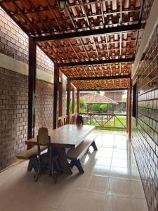 einen Holztisch und Stühle in einem Zimmer mit Ziegelwand in der Unterkunft Chalé da Serra - bem equipado e aconchegante para 10 pessoas em Gravatá/PE in Gravatá