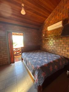 ein Schlafzimmer mit einem Bett in einer Ziegelwand in der Unterkunft Chalé da Serra - bem equipado e aconchegante para 10 pessoas em Gravatá/PE in Gravatá