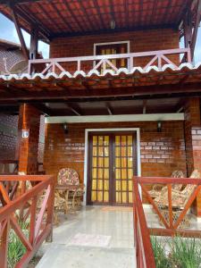 ein Backsteinhaus mit einer Veranda mit einem Holzzaun in der Unterkunft Chalé da Serra - bem equipado e aconchegante para 10 pessoas em Gravatá/PE in Gravatá